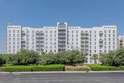 a large white building with trees in front of a street at 2BR in Safi Balcony Walk to Town Sq Park in Dubai