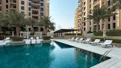 a large swimming pool with white chairs and buildings at Modern and family friendly 1 bed in Dubai