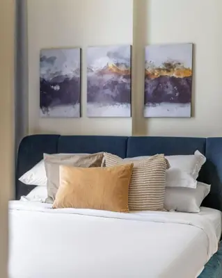 a white bed with four pictures on the wall at GuestReady - Contemporary elegance in Dubai in Dubai