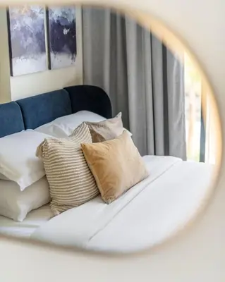 a mirror reflecting a bed with pillows on it at GuestReady - Contemporary elegance in Dubai in Dubai