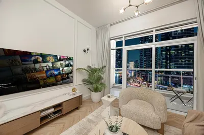 a living room with a large tv and a chair at Marina Waterfront Bliss - Steps from Promenade in Dubai