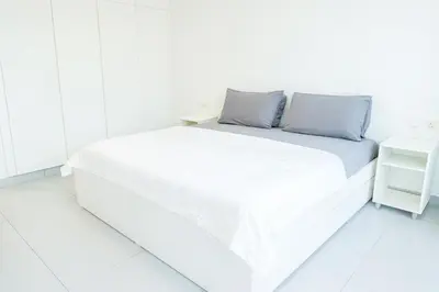a white bed with white sheets and blue pillows at New Large 2BR Apt Sleeps 10 Adults with Pool Gym Parking and Wifi in Dubai