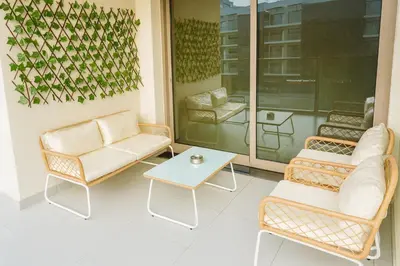 a porch with two chairs and a table and a couch at New Large 2BR Apt Sleeps 10 Adults with Pool Gym Parking and Wifi in Dubai