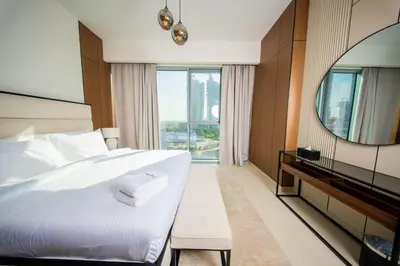 a bedroom with a large white bed and a mirror at Luxury 1 Bedroom Canalfront Apartment with Burj Khalifa Views from Resort-Style Pool - Walk to Jumeirah Beach in Dubai