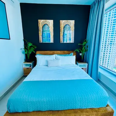 a blue bedroom with a bed with blue walls and windows at Marina Oasis JBR Beach in Dubai