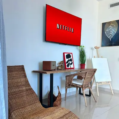 a living room with a table and a television on the wall at Marina Oasis JBR Beach in Dubai
