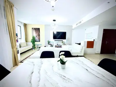 a large white room with a table with flowers on it at WAHA WOW Bed space Available in Luxury Apartment in Sabkhah