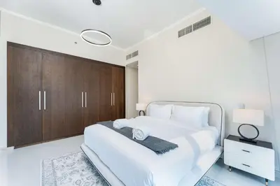 a white bedroom with a large white bed and wooden cabinets at PVH - Iconic Waterfront Escape - Luxury 2BR with Sea Views - DUBAI MARINA in Dubai
