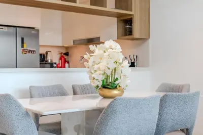 a dining room table with a vase of flowers on it at TRPS - Downtown Views II T2, Downtown Dubai - Modern 3BR Home, Maids Room, Full Burj Khalifa View in Dubai