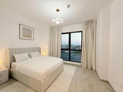 a white bedroom with a bed and a large window at Stunning 3BR Retreat with Panoramic Sunset Views in Dubai