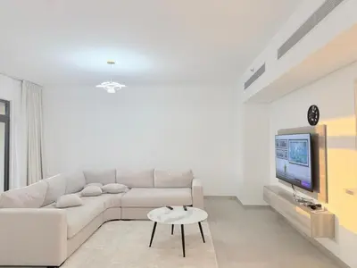 a white living room with a white couch and a tv at Stunning 3BR Retreat with Panoramic Sunset Views in Dubai