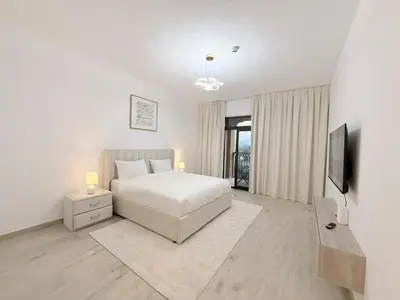a white bedroom with a bed and a television at Stunning 3BR Retreat with Panoramic Sunset Views in Dubai