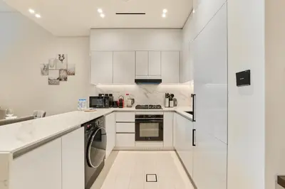 a white kitchen with white cabinets and appliances at Elegant 2BR Ground Floor Escape in Binghatti Galaxy JVC in Dubai