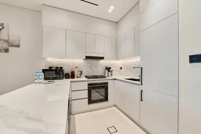 a white kitchen with white cabinets and appliances at Elegant 2BR Ground Floor Escape in Binghatti Galaxy JVC in Dubai