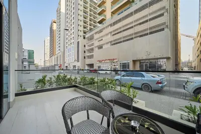 a balcony with chairs and a table and a car on a street at Elegant 2BR Ground Floor Escape in Binghatti Galaxy JVC in Dubai