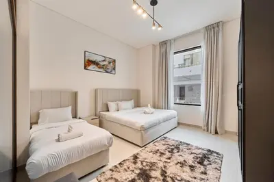 a hotel room with two beds and a window at Elegant 2BR Ground Floor Escape in Binghatti Galaxy JVC in Dubai