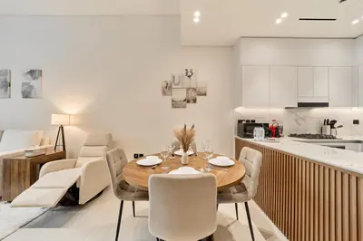 a kitchen and dining room with a wooden table and chairs at Elegant 2BR Ground Floor Escape in Binghatti Galaxy JVC in Dubai