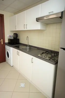 a kitchen with white cabinets and a sink and a stove at Sunsand Studio at Dubai Marina in Dubai