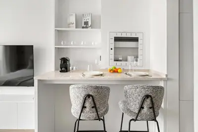 a kitchen with a counter with two chairs and a microwave at Chic Modern Studio in Meydan Azizi Riviera 26 in Dubai