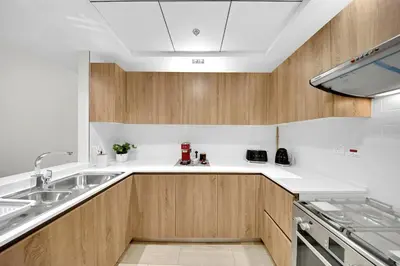 a kitchen with wooden cabinets and a sink at 10 min to Dubai Marina - New Cozy 1 Bed in JVT in Dubai