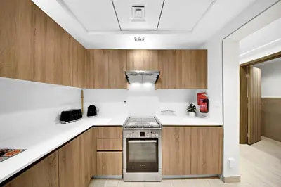 a kitchen with wooden cabinets and a stove at 10 min to Dubai Marina - New Cozy 1 Bed in JVT in Dubai