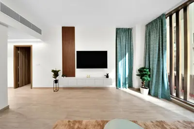 a living room with a flat screen tv on a wall at 10 min to Dubai Marina - New Cozy 1 Bed in JVT in Dubai