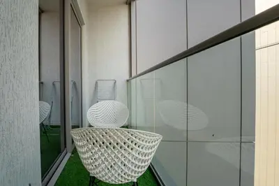 a balcony with white chairs and a table at HAVN - 1 bedroom in Sobha Creek, MBR City in Dubai