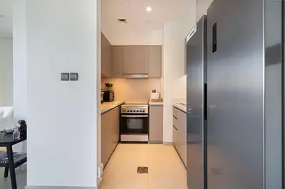 a small kitchen with a stainless steel refrigerator at Luxury Downtown 2 Bedroom Apartment with amazing Burj and Fountain Views and Private Jacuzzi on a large Terrace in Dubai