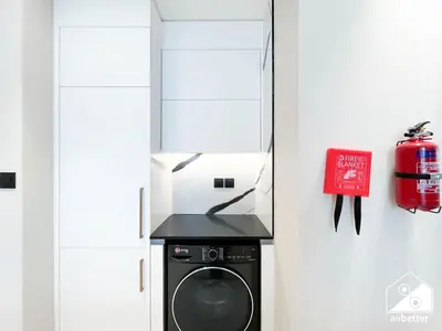 a kitchen with a washing machine and a fire extinguisher at 2BR Panoramic Skyline Haven with Jacuzzi in Dubai