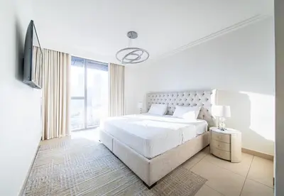 a white bedroom with a large bed and a window at Luxury 2 Bed in Boulevard Point with City Views in Dubai