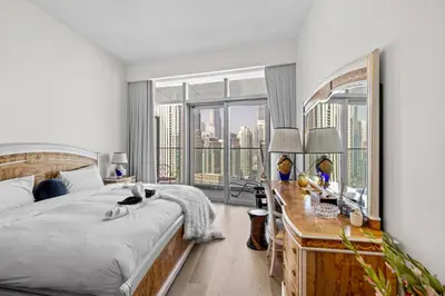 a bedroom with a bed and a desk with a large window at Elegant 3 BR plus Maids Infinity Pool Burj View in Dubai