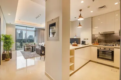 a kitchen with white cabinets and a living room at BLVD - Stunning Full Burj Khalifa Firework Views in Dubai