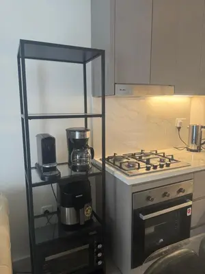 a kitchen with a stove top oven next to a shelf at Holiday homes azizi riviera in Dubai