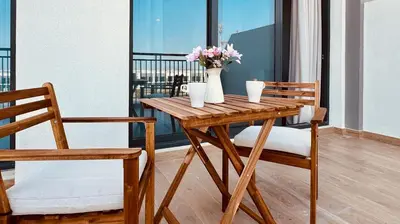 a wooden table with two chairs and a vase with flowers at Premium Guest - Liva Serenity Suite in Dubai