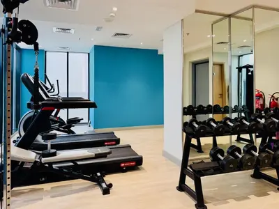 a gym with tread machines and a blue wall at Premium Guest - Dubai Riviera in Dubai