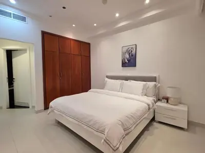 a bedroom with a large bed and a wooden cabinet at Luxury Furnished 2 BR with Stunning Sea View in Dubai