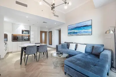 a living room with a blue couch and a table at StayMada - Ocean Heights Marina City and Sea Views in Dubai