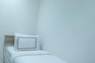 a bed with white sheets and a pillow on it at Gemz by Danube, Private Pool, Al Furjan - Onelink in Dubai