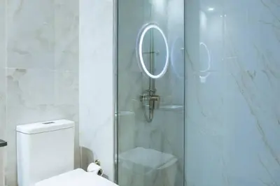 a bathroom with a shower with a toilet and a mirror at Gemz by Danube, Private Pool, Al Furjan - Onelink in Dubai