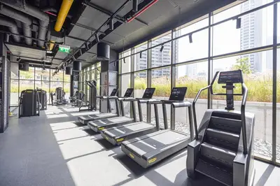 a row of treadmills in a gym with windows at Trendy & Brand new Studio In Business Bay in Dubai