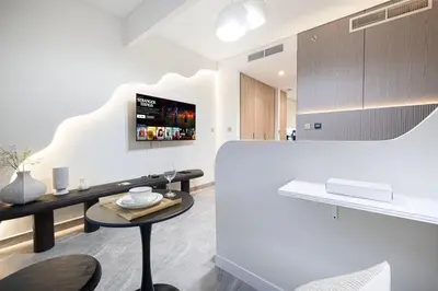 a white kitchen with a table and a counter at Trendy & Brand new Studio In Business Bay in Dubai