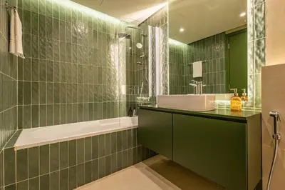 a green tiled bathroom with a sink and a tub at Designer's Selection - Luxury in the Heart of DIFC in Dubai