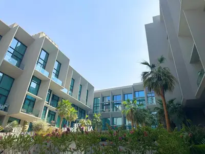 an apartment building with palm trees in front of it at Luxury Studio with Balcony, Pool, Coworking in JVC in Dubai