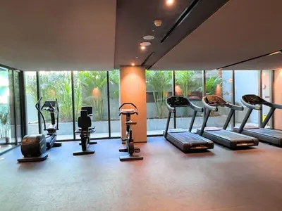 a gym with many cardio machines in a room with windows at Luxury Studio with Balcony, Pool, Coworking in JVC in Dubai