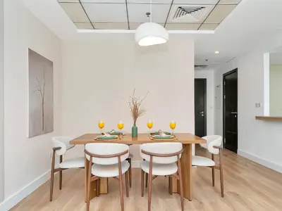 a dining room with a wooden table and white chairs at Luxury Waterfront View w Ain Dubai and PS5 in JBR 5 min from the beach in Dubai