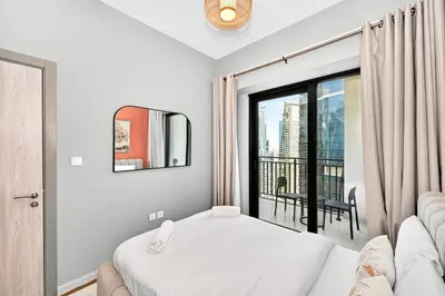 a bedroom with a bed and a large window at Golden Stays - Cozy 1BR Retreat I Skyline Views & Urban Charm in Dubai