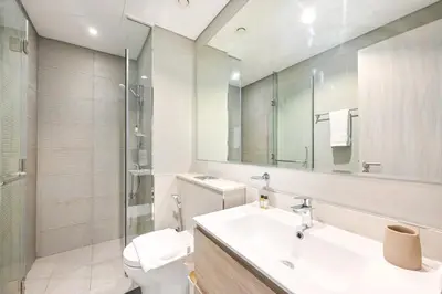 a bathroom with a sink and a toilet and a mirror at Golden Stays - Cozy 1BR Retreat I Skyline Views & Urban Charm in Dubai