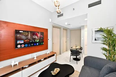 a living room with a tv on a wall at Golden Stays - Cozy 1BR Retreat I Skyline Views & Urban Charm in Dubai