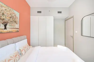a bedroom with a white bed and an orange wall at Golden Stays - Cozy 1BR Retreat I Skyline Views & Urban Charm in Dubai