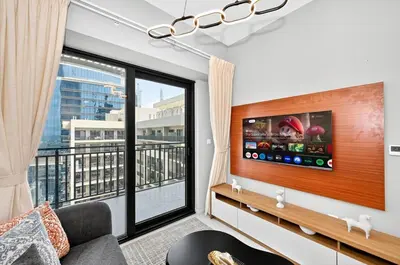 a living room with a tv and a large window at Golden Stays - Cozy 1BR Retreat I Skyline Views & Urban Charm in Dubai